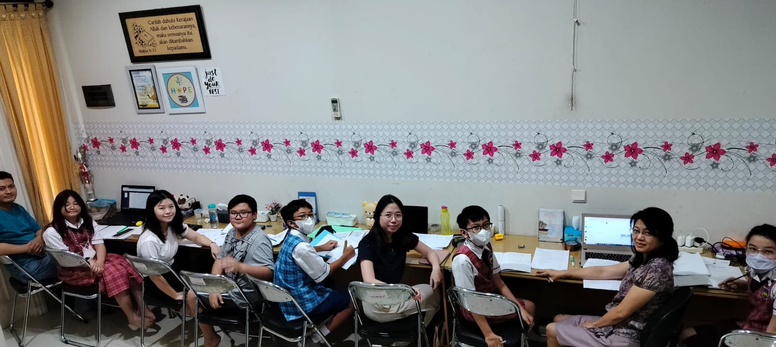 Siswa belajar bersama tutor di meja panjang